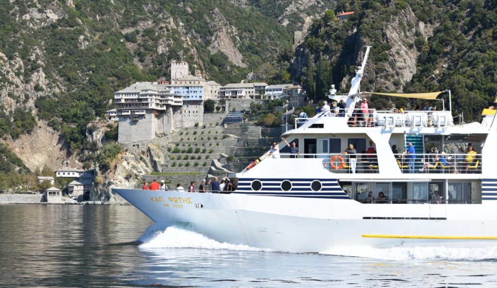 Boat for Athos and Ammouliani cruise sailing along the coast of Mount Athos with cliffs and blue sea
