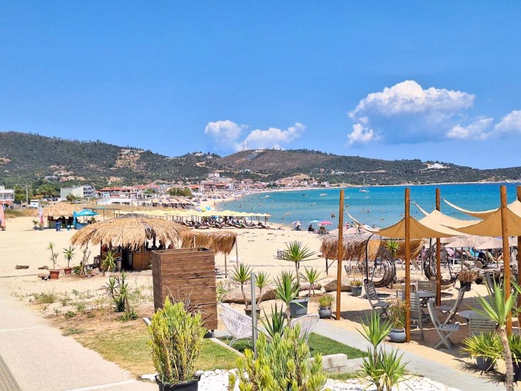 Sarti City Beach in Sithonia with straw sun umbrellas and clear blue sea