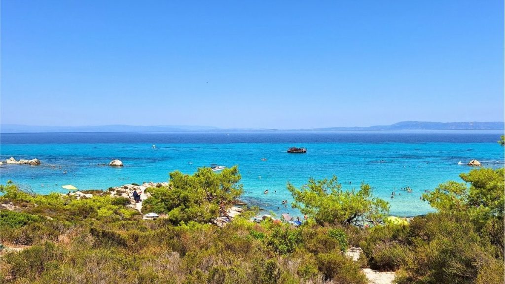 Turquoise blue sea with green bushes in front at Orange Beach, Kavourotripes, Sithonia
