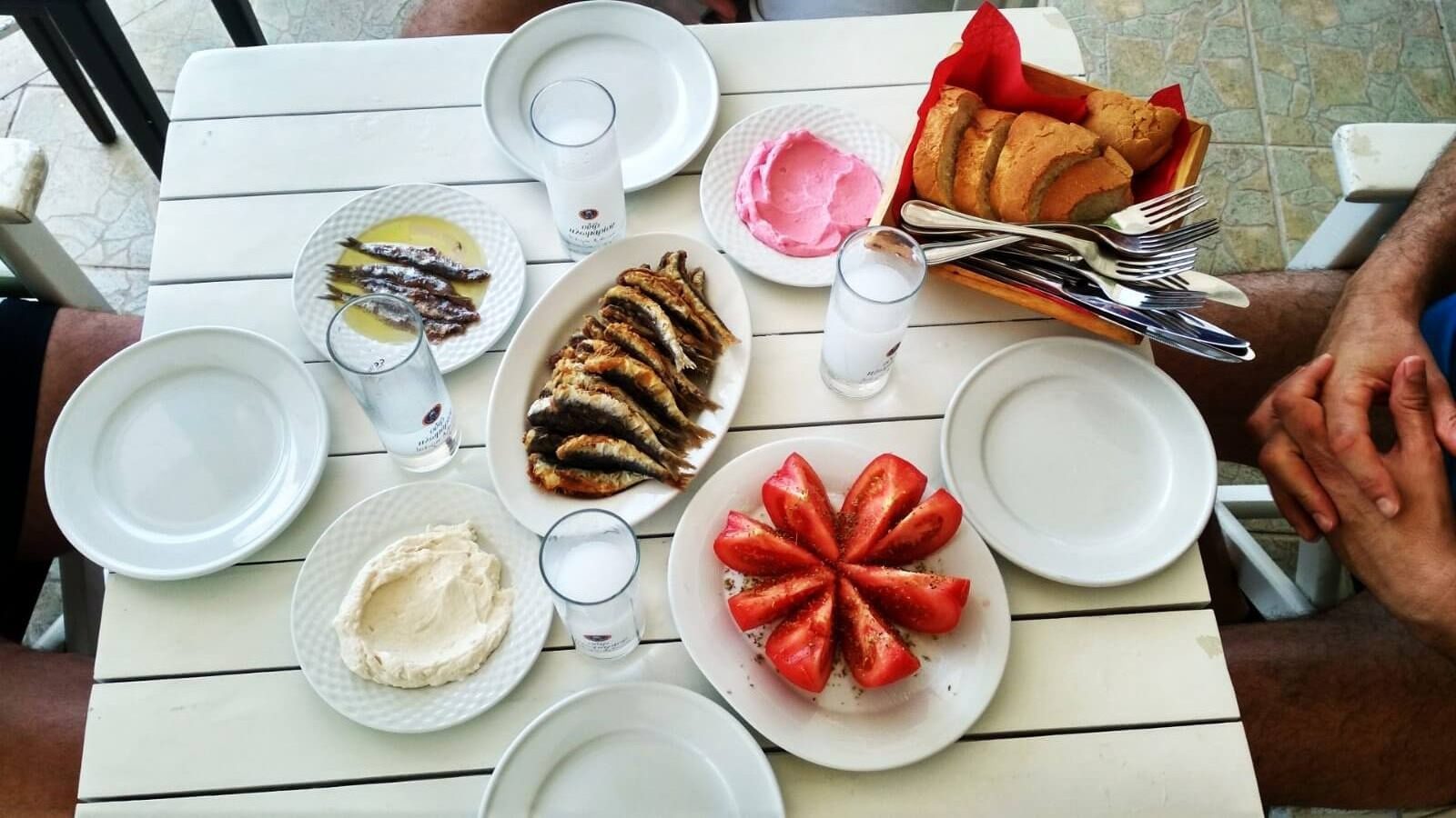 Greek meze platter with sardines and ouzo on a wooden table
