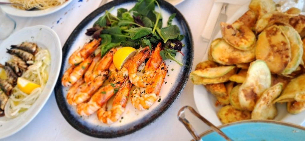 Fresh seafood lunch with grilled shrimp, sardines and fried zucchini in Sithonia Greece