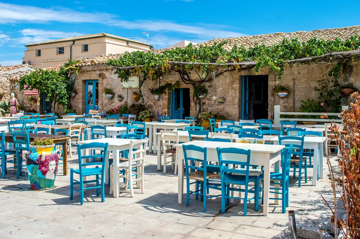 Traditional Greek taverna with checkered tablecloths and wooden chairs in a cozy seaside setting